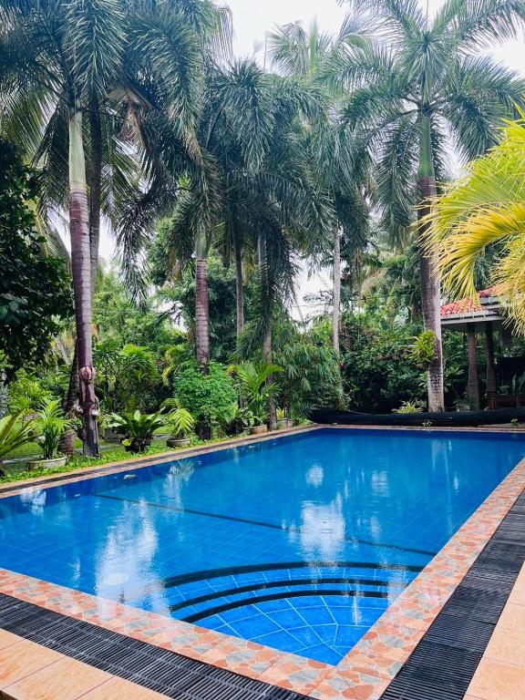a blue swimming pool with palm trees in the background at Pavana Hotel Negombo in Negombo