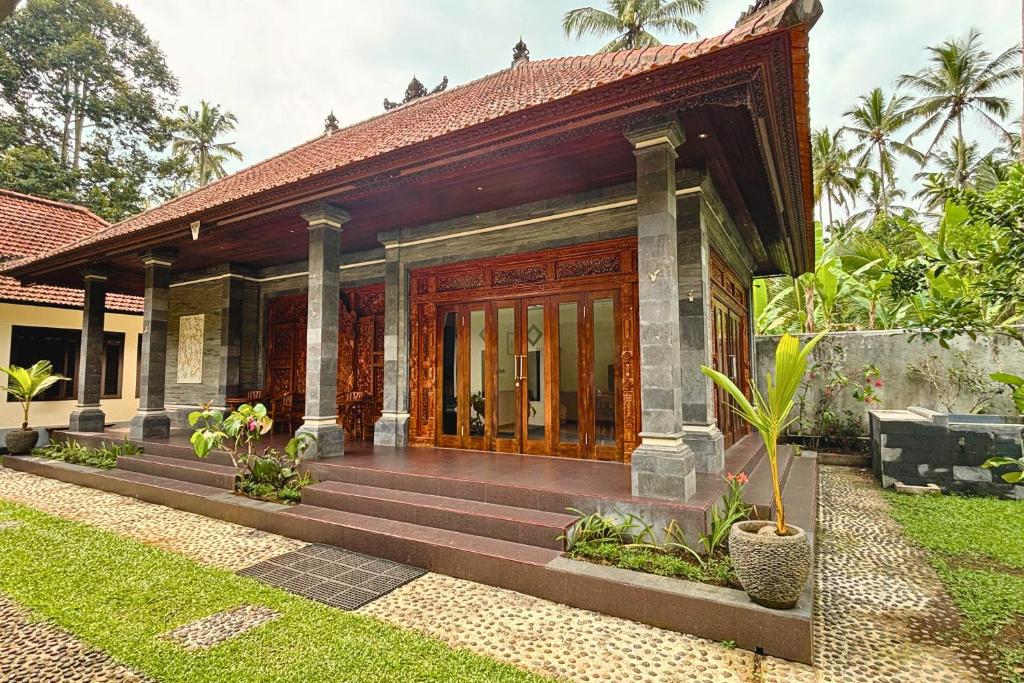 a house with wooden doors and a yard at Arisa Villa by AGATA in Bangli