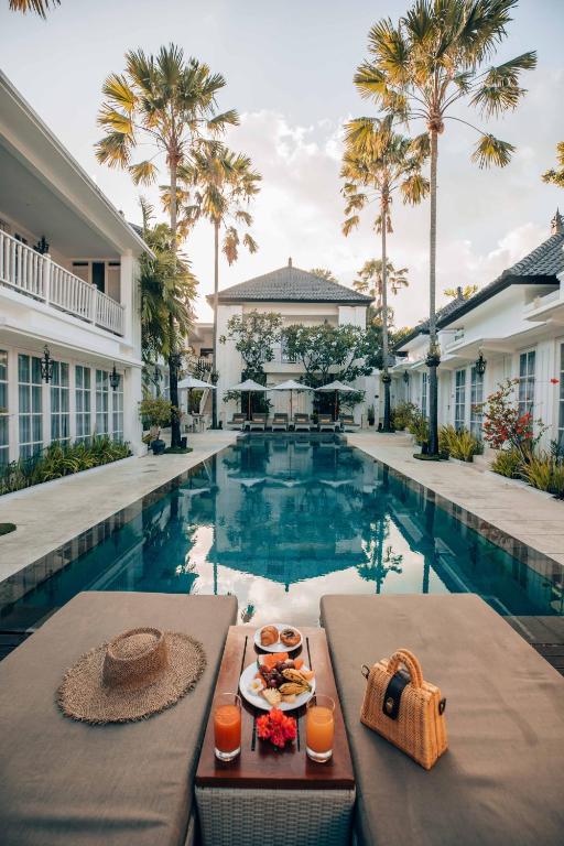 a table with a tray of food next to a swimming pool at The Colony Hotel Bali in Seminyak