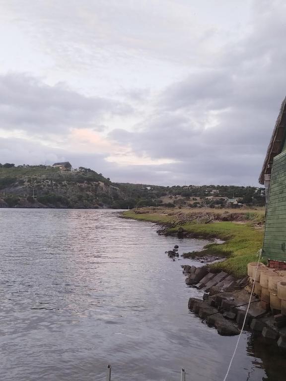 a view of a river with a building and rocks at Rivers edge cottage in Stilbaai