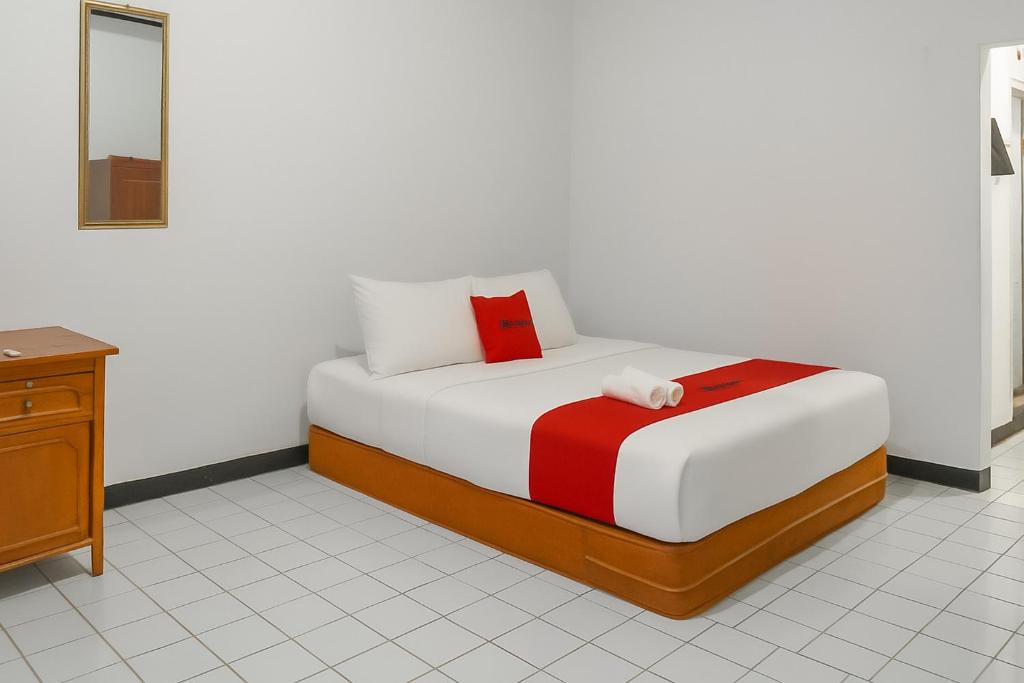 a bedroom with a bed with a red pillow on it at RedDoorz Syariah at Serenity Guesthouse Subang in Subang