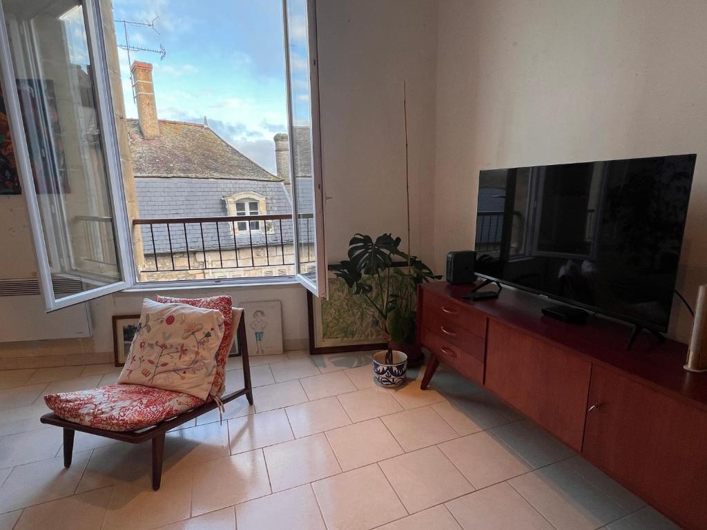 un salon avec une télévision à écran plat et une chaise dans l'établissement Chambre privative au calme en plein centre avec balcon, à Avallon
