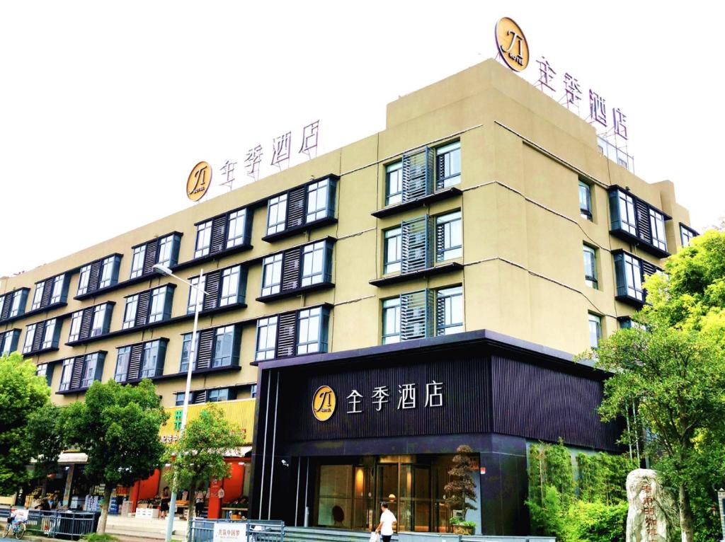 a building with a person walking in front of it at 全季上海顾村公园菊联路酒店JI Hotel Shanghai Gucun Park Julian Road in Shanghai