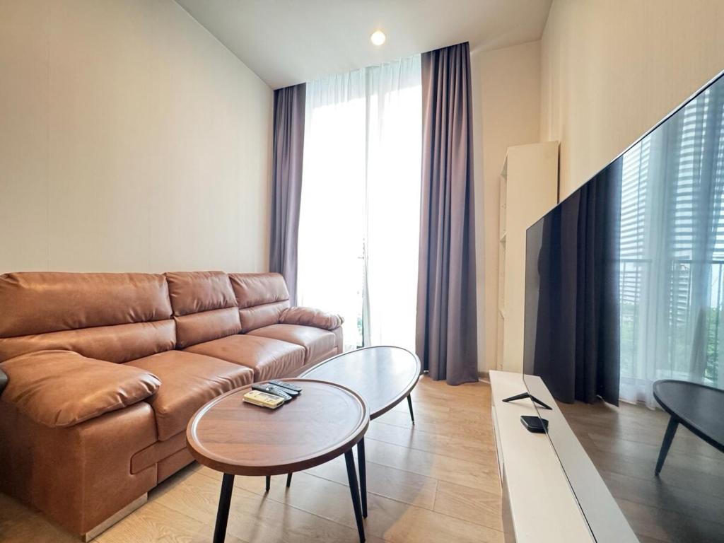 a living room with a brown couch and a table at Noble Bangkok Condo in Bangkok