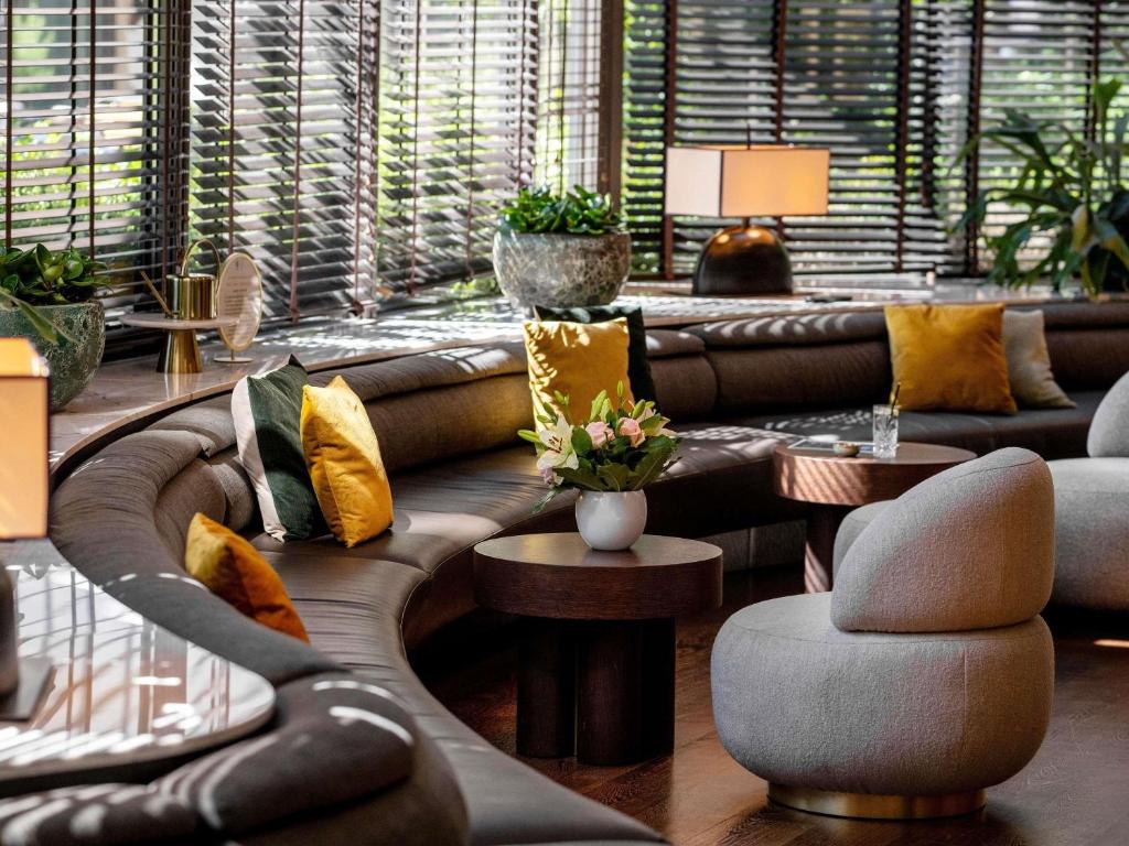 a living room with a leather couch and chairs at Le Louise Hotel Brussels - MGallery Collection in Brussels