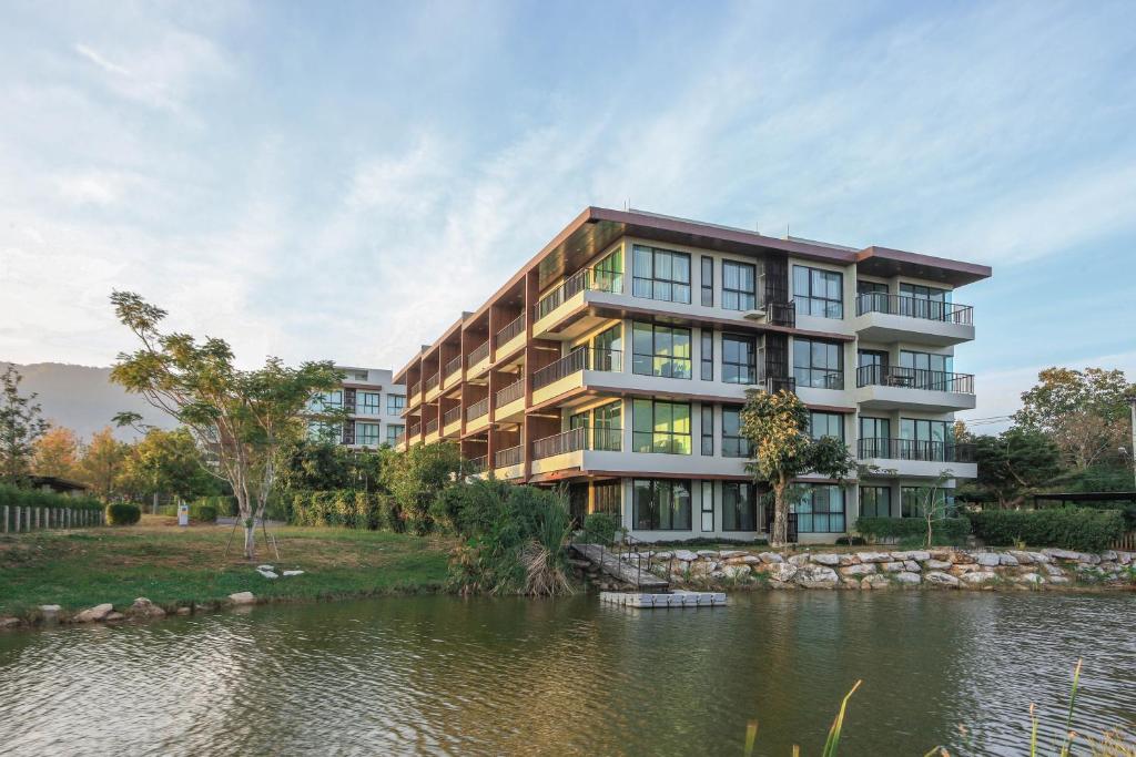 an apartment building next to a body of water at The H2O Khao Yai in Ban Rai Khlong Sai