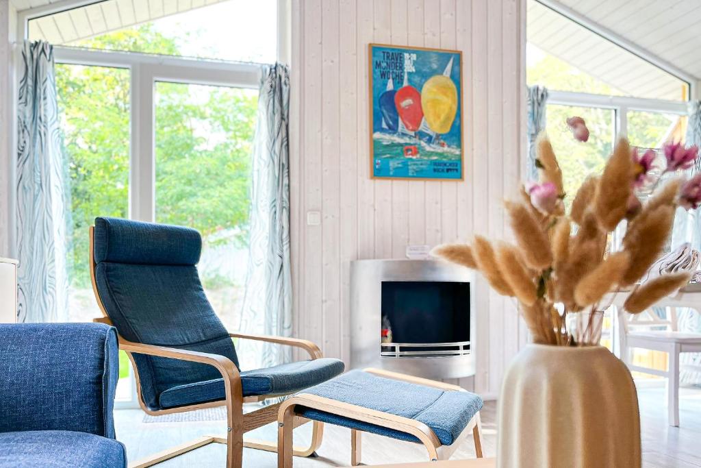 a living room with a blue chair and a vase with flowers at Schatzkiste - Dorf Ferienhaus 18 in Priwall