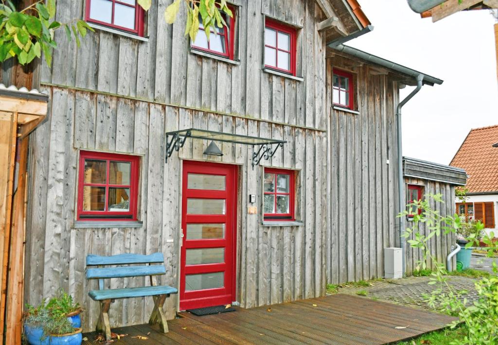 a barn with a red door and a blue bench at Ferienwohnung mit Dachterrasse Kamin nahe dem Strelasund in Franken Vorstadt
