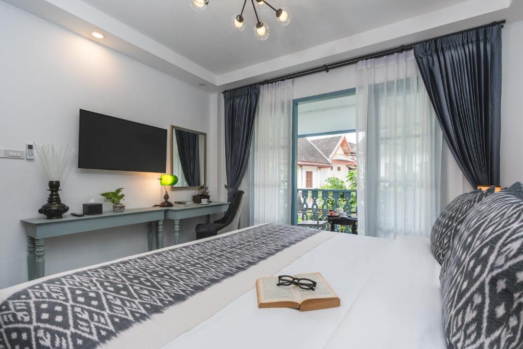a bedroom with a bed with a book and a window at Luangprabang D'or Boutique Hotel in Luang Prabang