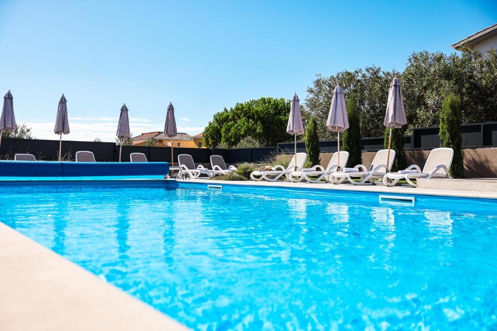 a swimming pool with chairs and umbrellas at Villa Lucy Apartments in Vir