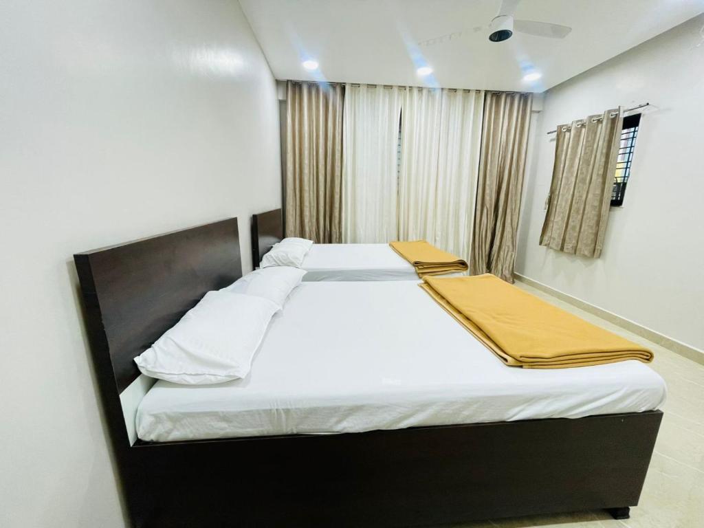 a bedroom with a large bed with white sheets at Maheshwari Bhakt Niwas And Homestay in Tuljapur