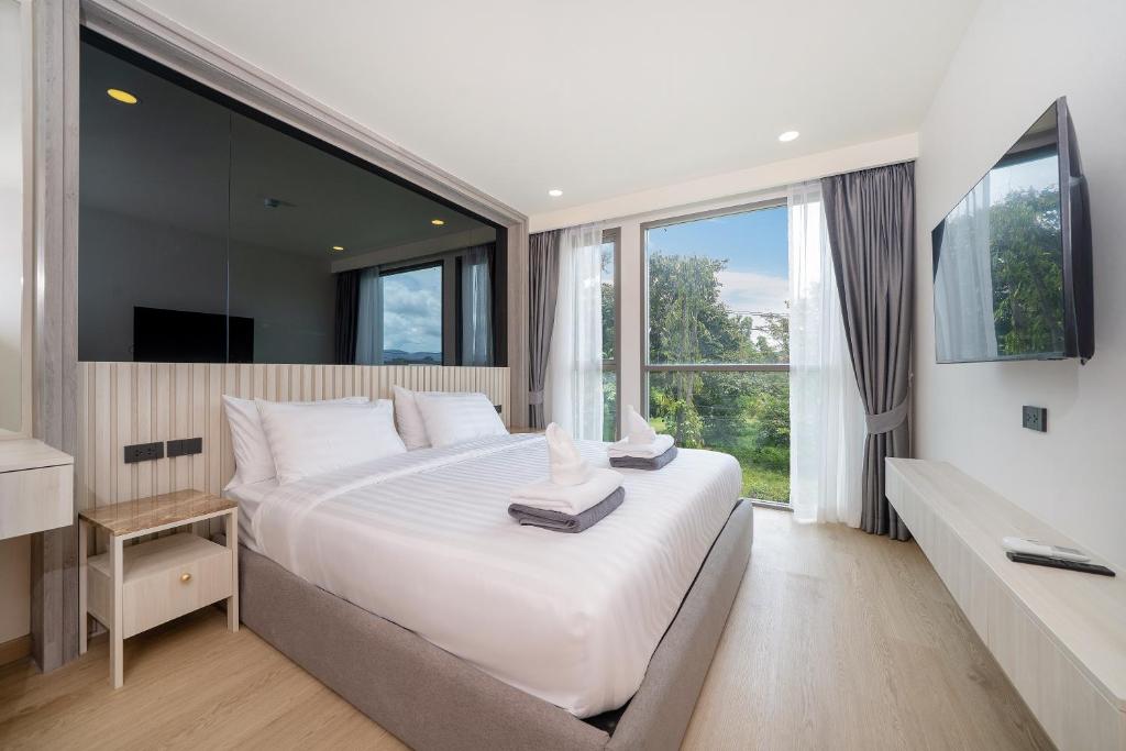 une chambre avec un grand lit blanc et une grande fenêtre dans l'établissement Ozone 2 Bed Condominium in Splendid Laguna Area, à Laguna Phuket