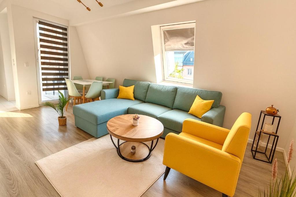 ein Wohnzimmer mit einem blauen Sofa und gelben Stühlen in der Unterkunft Neubauwohnung in Siegen-Zentrum in Siegen