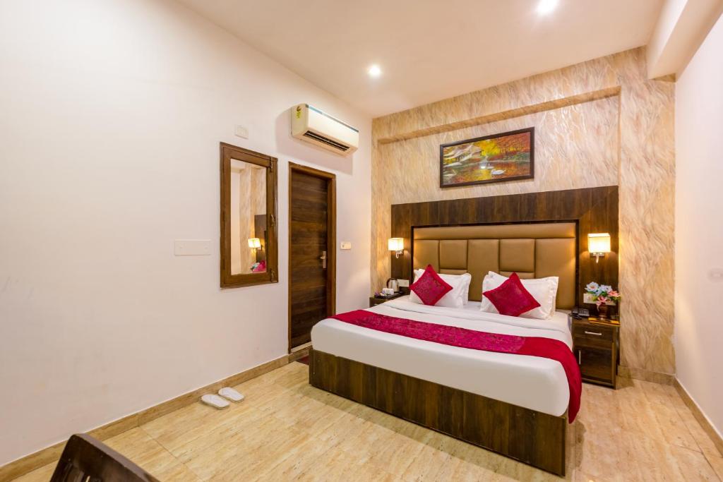 a bedroom with a large bed with red pillows at Hotel Kiara - Near Delhi Airport in New Delhi