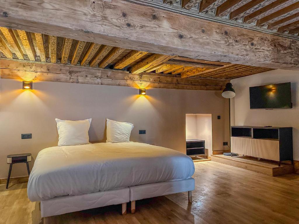 a bedroom with a large white bed and wooden ceilings at Le Refuge de la Bastille - Jacuzzi in Grenoble