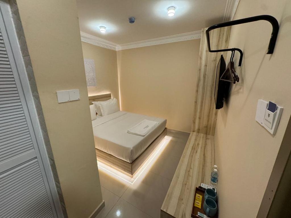 a small bedroom with a small bed in a room at Blenz Hotel in Serdang
