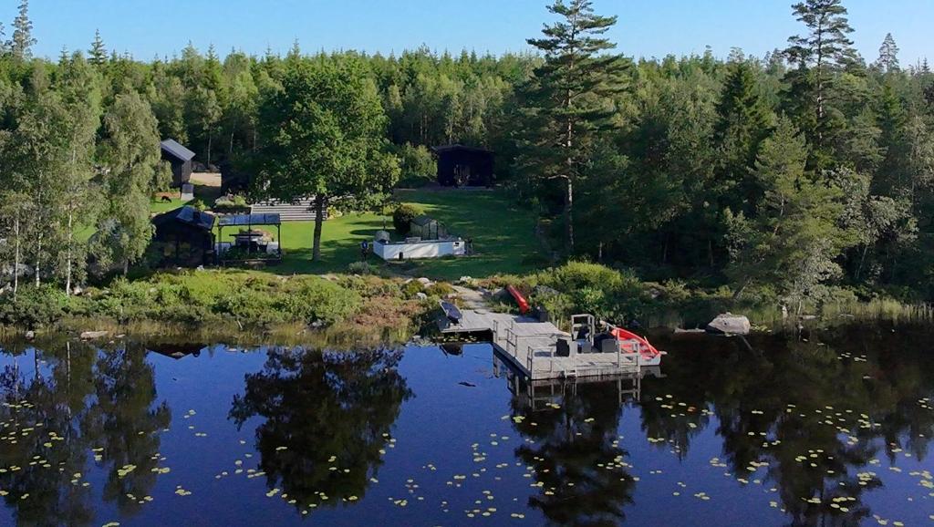 una vista aerea di un lago con una casa e alberi di Lakehouse med bastu, egen brygga och roddbåt a Målsryd