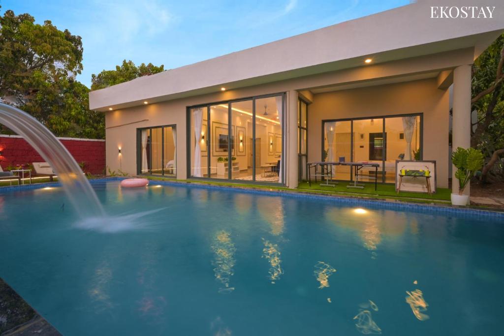 a swimming pool in front of a house at EKOSTAY Luxe - Ivory Coast Villa in Alibaug