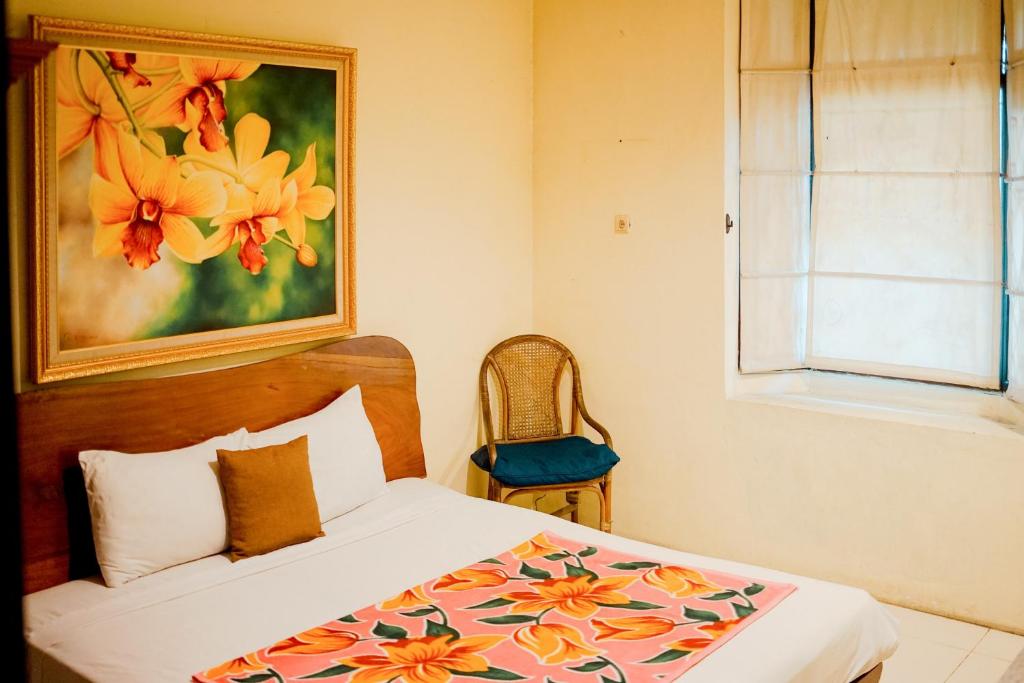 a bedroom with a bed with a painting on the wall at My Cafe Hotel near UGM Yogyakarta Mitra RedDoorz in Kejayan