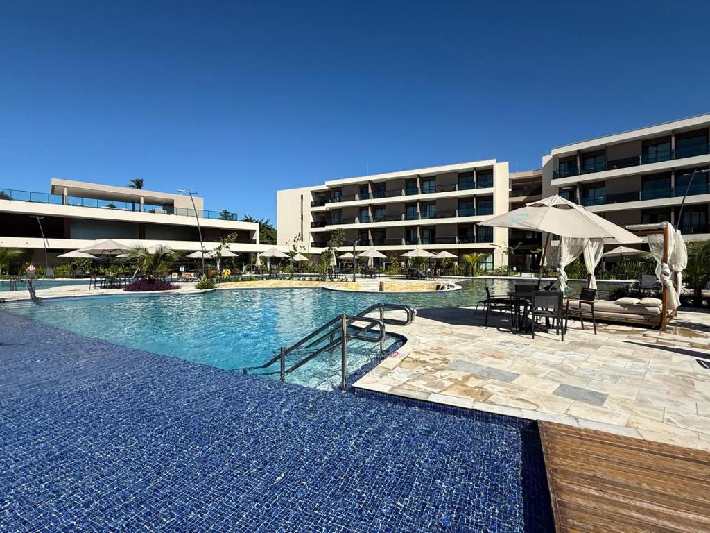a swimming pool with chairs and umbrellas in a building at MALIA BEACH - Alto Padrão - PRAIA MURO ALTO - Porto de Galinhas in Porto De Galinhas