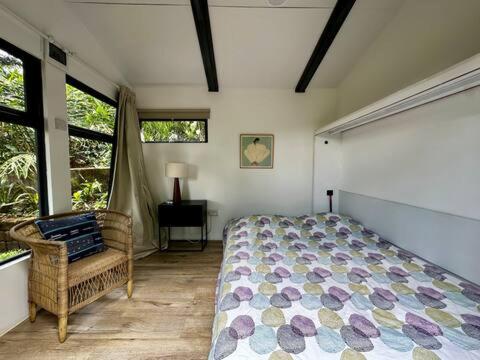 een slaapkamer met een bed, een stoel en ramen bij Nairobi Botanical Retreat - Container Home in Nairobi