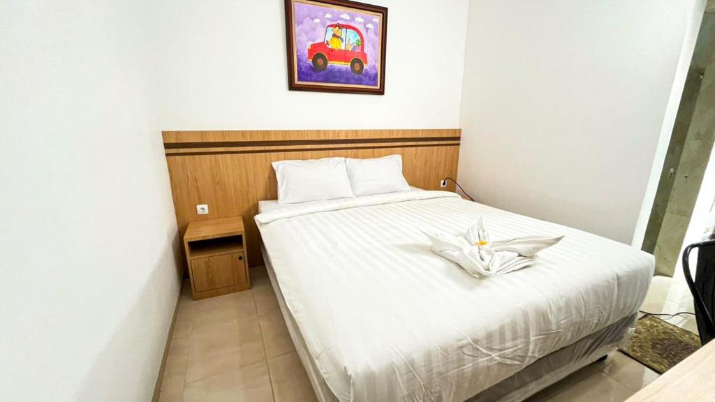 a bedroom with a white bed and a painting on the wall at The Cabin Hotel Sumberan Baru in Ngabean