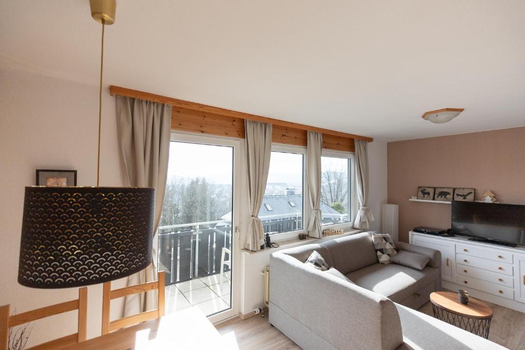 un salon avec un canapé et une grande fenêtre dans l'établissement Winterberg View - Balkon mit Südblick - zentrale Lage - eigener Parkplatz, à Winterberg