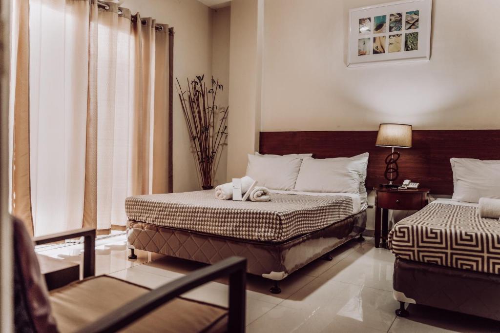 a bedroom with two beds and a chair in it at Lenma Family Inn in Davao City