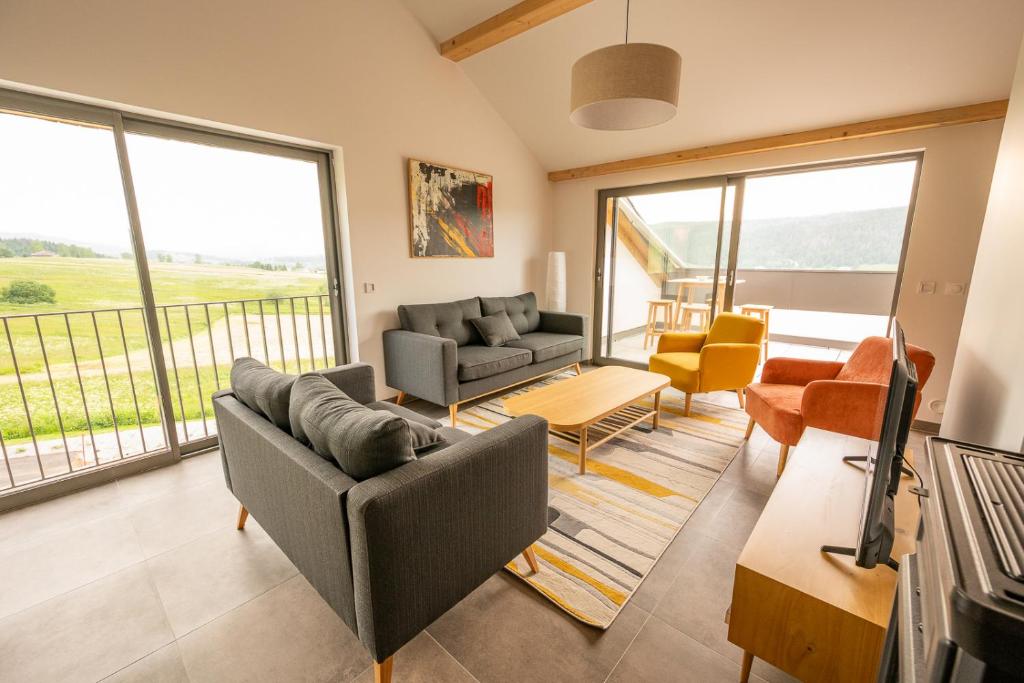 a living room with two couches and a tv at Le 240, entre lac et montagnes in Les Rousses