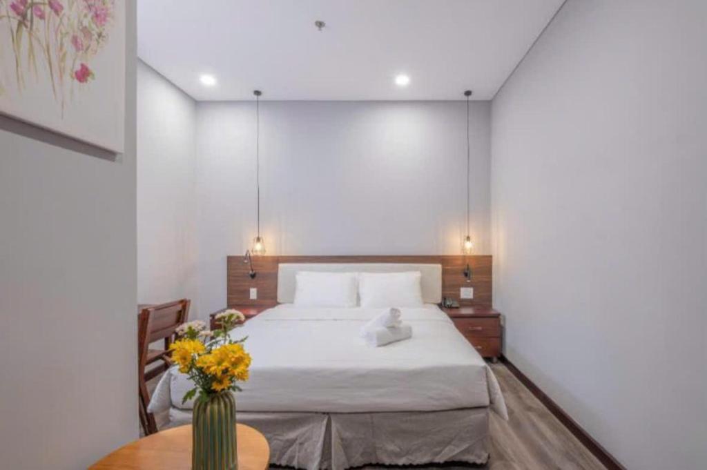 a bedroom with a bed and a table with flowers on it at Silana Riverfront Danang in Da Nang