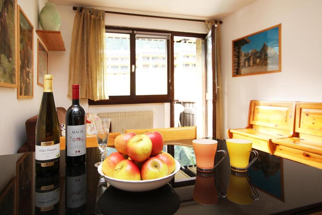 a table with a bowl of apples and two bottles of wine at WI-RO Mavignola - Trekking & Ski in Madonna di Campiglio