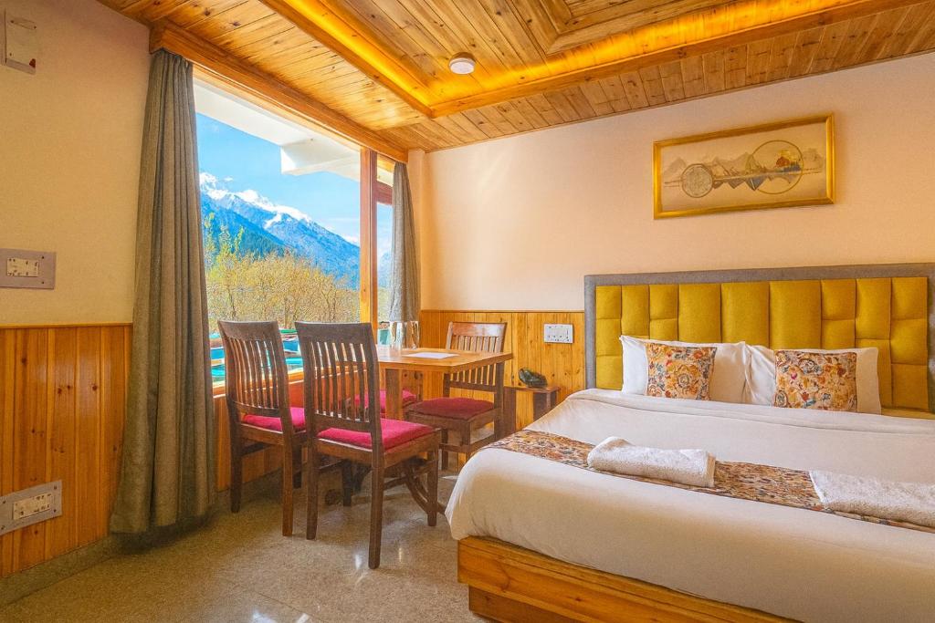 a bedroom with a bed and a table and chairs at Hotel Old Manali - Balcony Rooms with Mountain View, Garden & Parking in Manāli