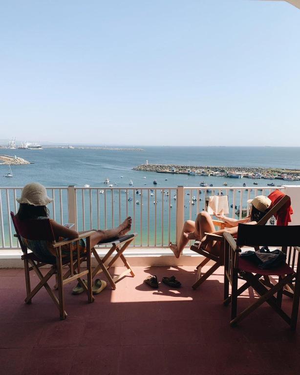three people sitting in chairs on a balcony looking at the ocean at Manas Slowliving - Sines in Sines