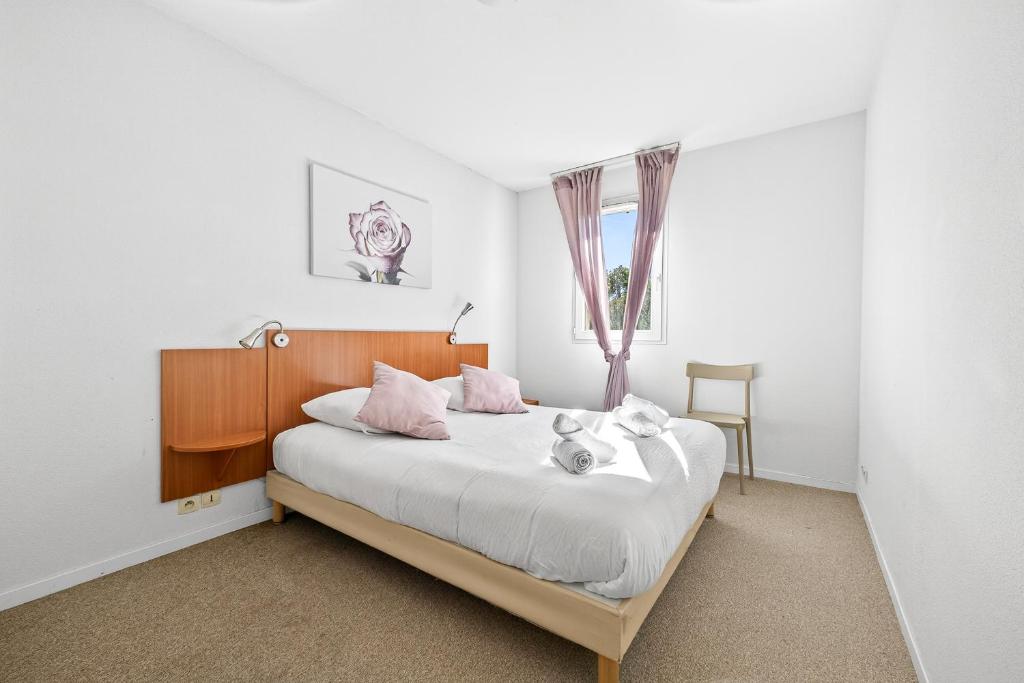 a bedroom with a bed with white sheets and pink pillows at Nova - Piscine - Climatisé - Proche Aix-en-Provence in Fuveau
