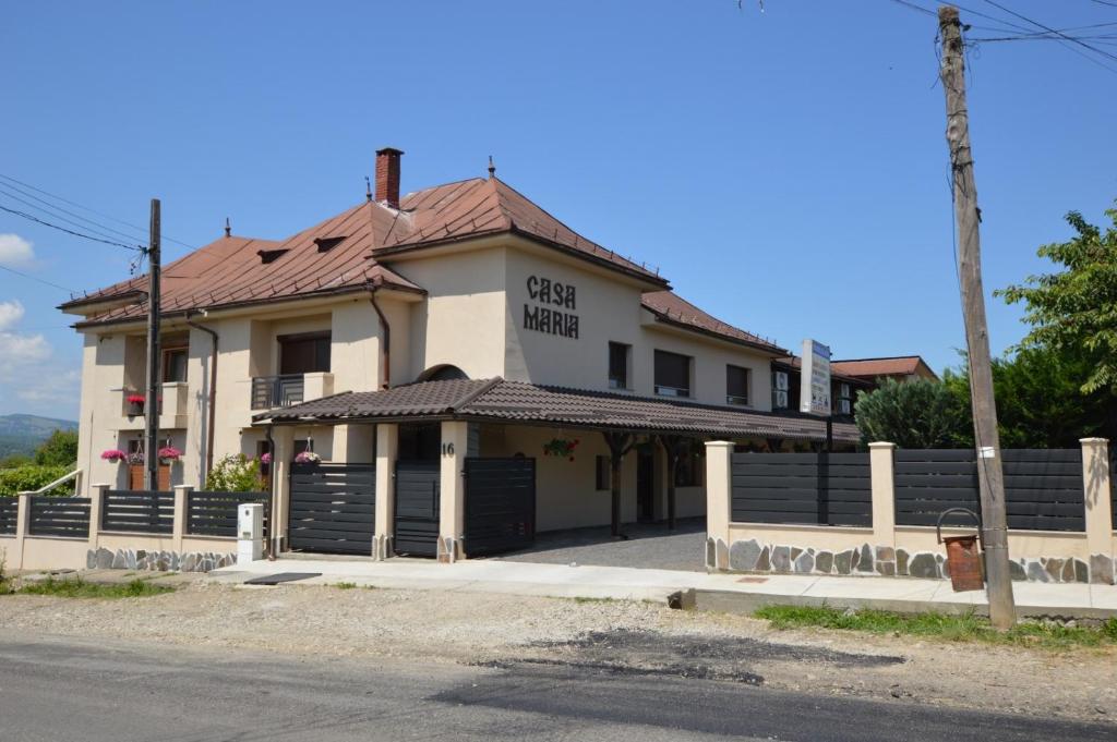 a building with a gate on the side of a street at Pensiunea Casa Maria in Săpînţa