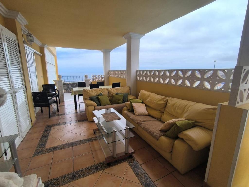 ein Wohnzimmer mit einem Sofa und einem Tisch auf dem Balkon in der Unterkunft Villa Costa Adeje in Adeje
