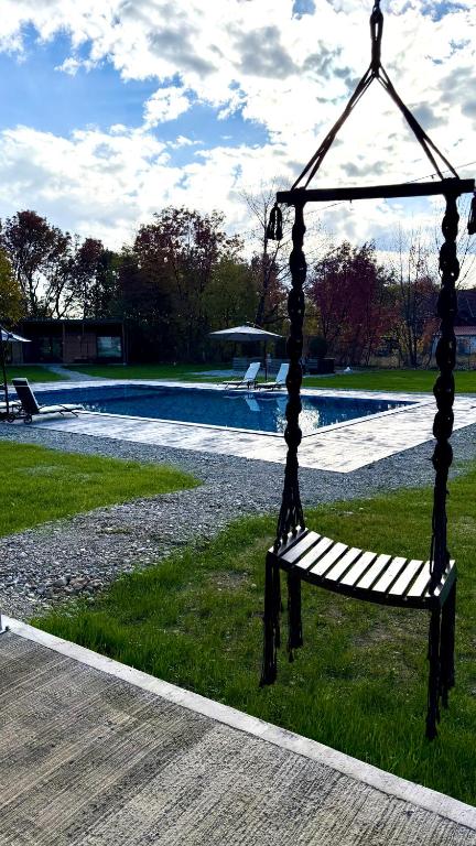 a bench sitting in the grass next to a pool at Badash Tiny Village - Tiny Houses with Heated Pool & BBQ in Polovragi