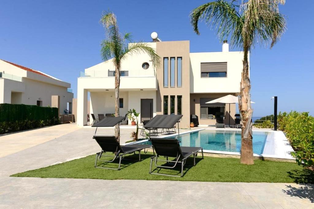 a villa with a swimming pool and palm trees at Aetheria Luxury Villa in Kalithies