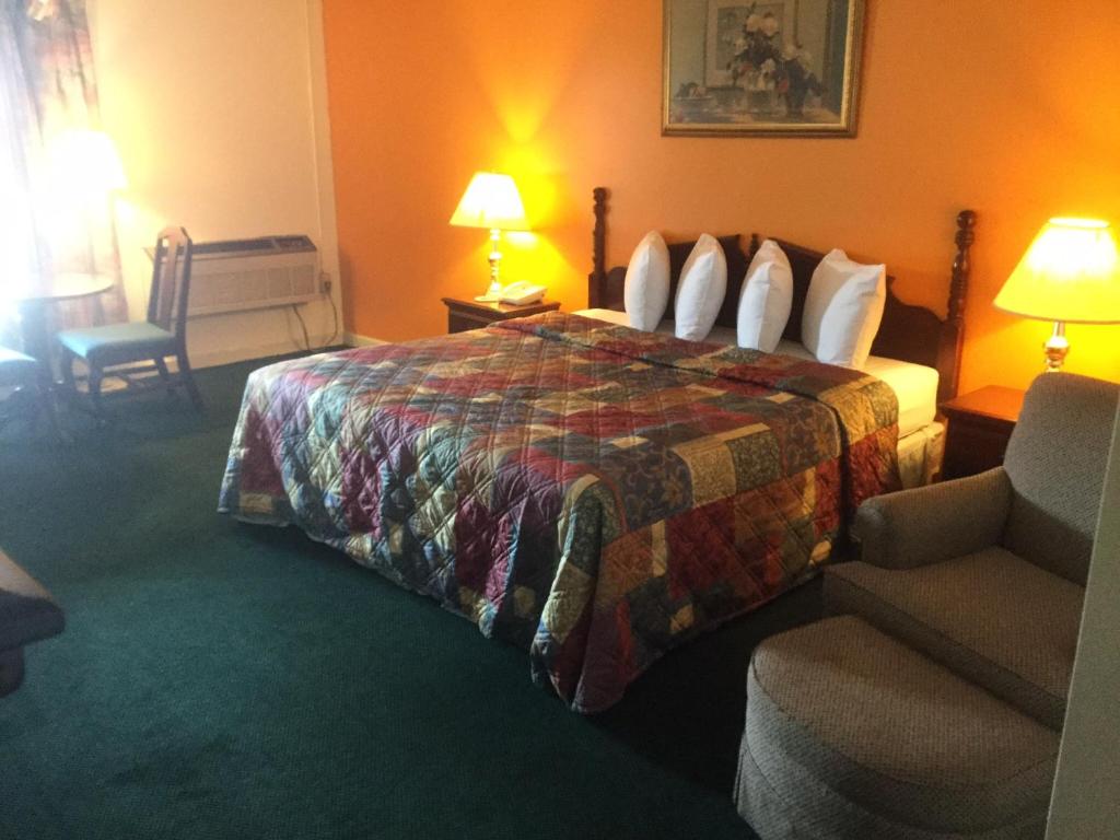 um quarto de hotel com uma cama e uma cadeira em Budget inn em Lumberton