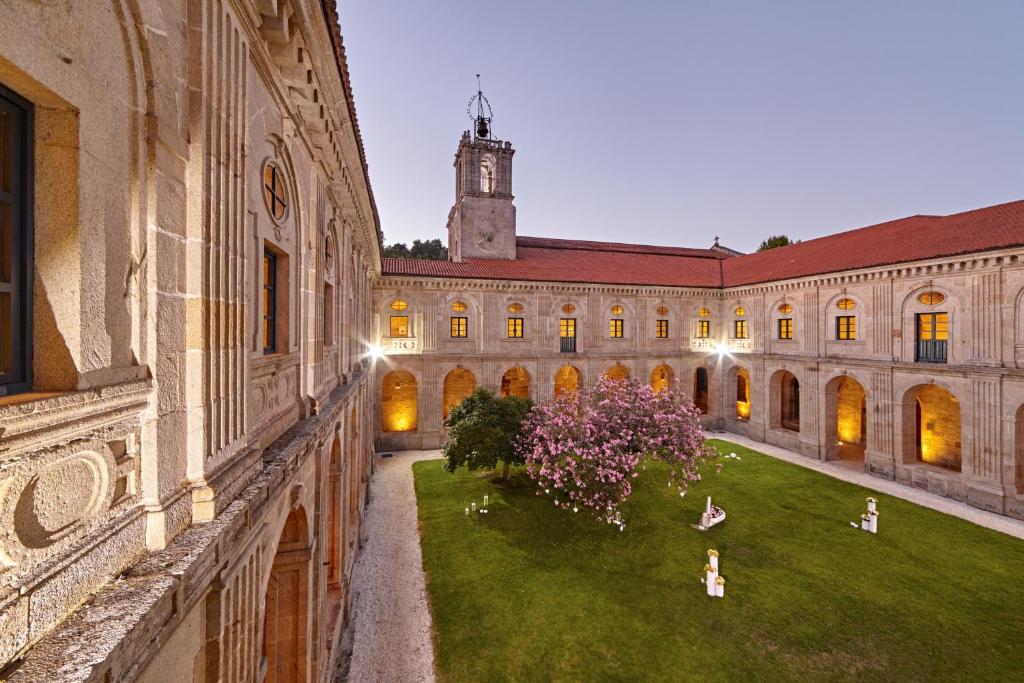 einen Innenhof eines Gebäudes mit Leuten auf dem Rasen in der Unterkunft Eurostars Monumento Monasterio de San Clodio Hotel in Leiro