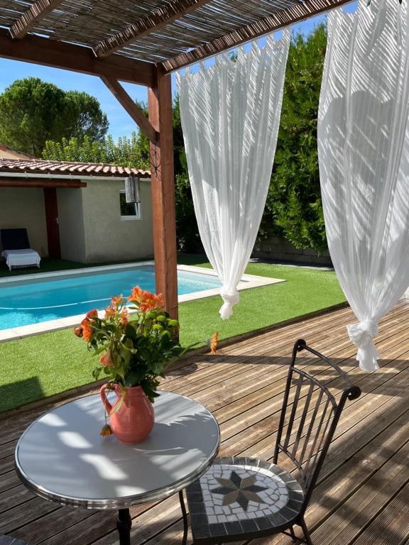a table and a chair and a vase on a deck at La casemate in LʼIsle-sur-la-Sorgue