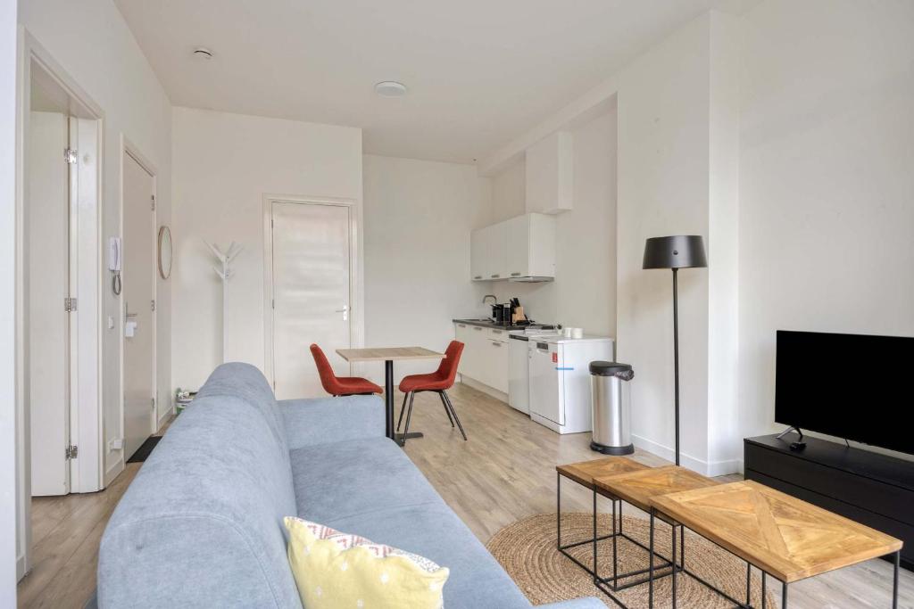 a living room with a blue couch and a table at Modern & Comfortable 1-Bedroom Flat in Rotterdam