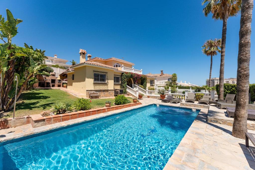 a swimming pool in front of a house with palm trees at Rustic Spanish Villa Saltwater Pool in Torrequebrada