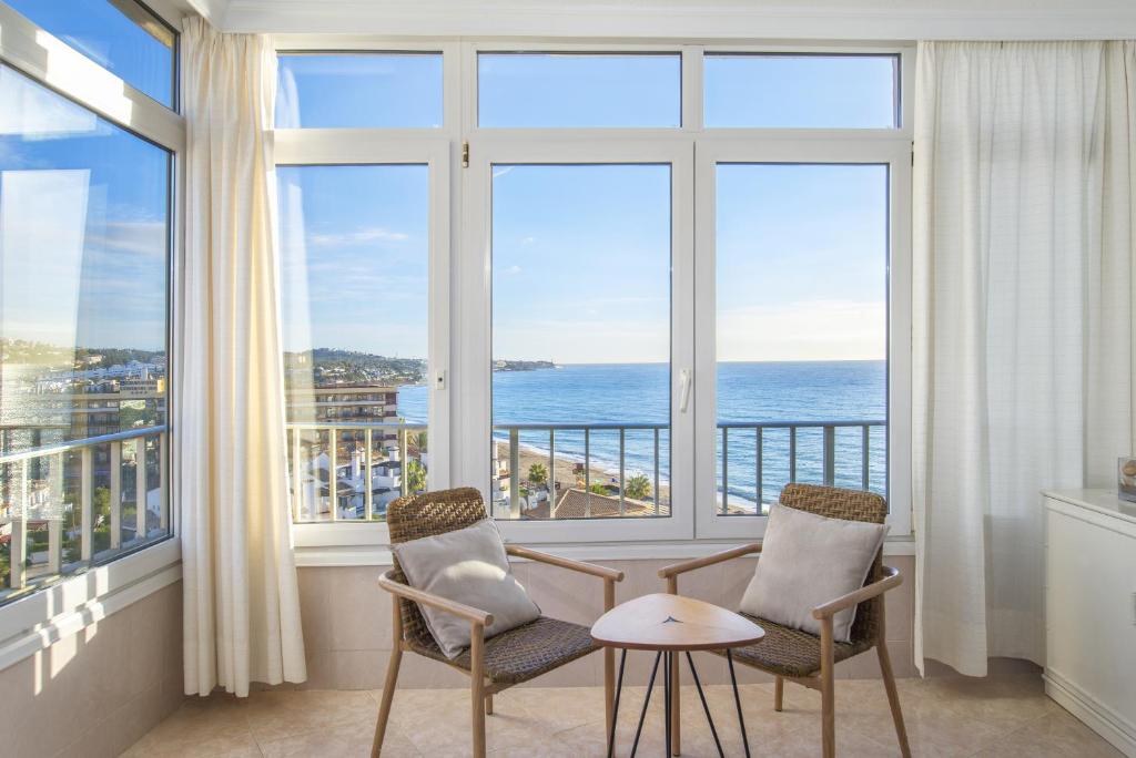 a room with two chairs and a table in front of windows at Penthouse studio with sea views in La Cala de Mijas