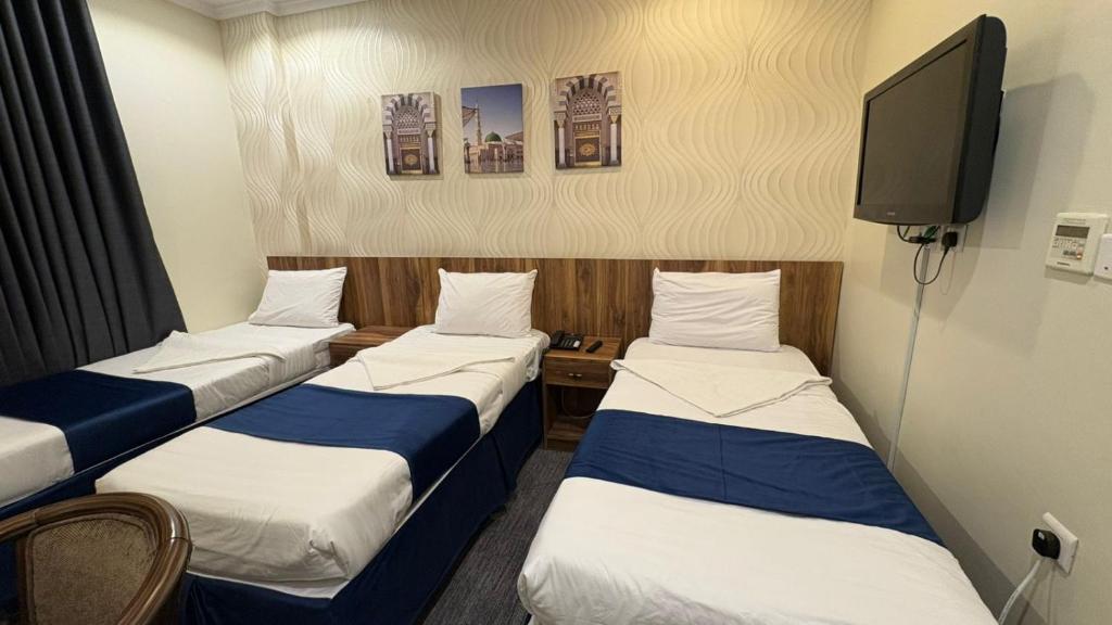 a room with three beds and a tv at فندق نزلي المعابدة in Miná