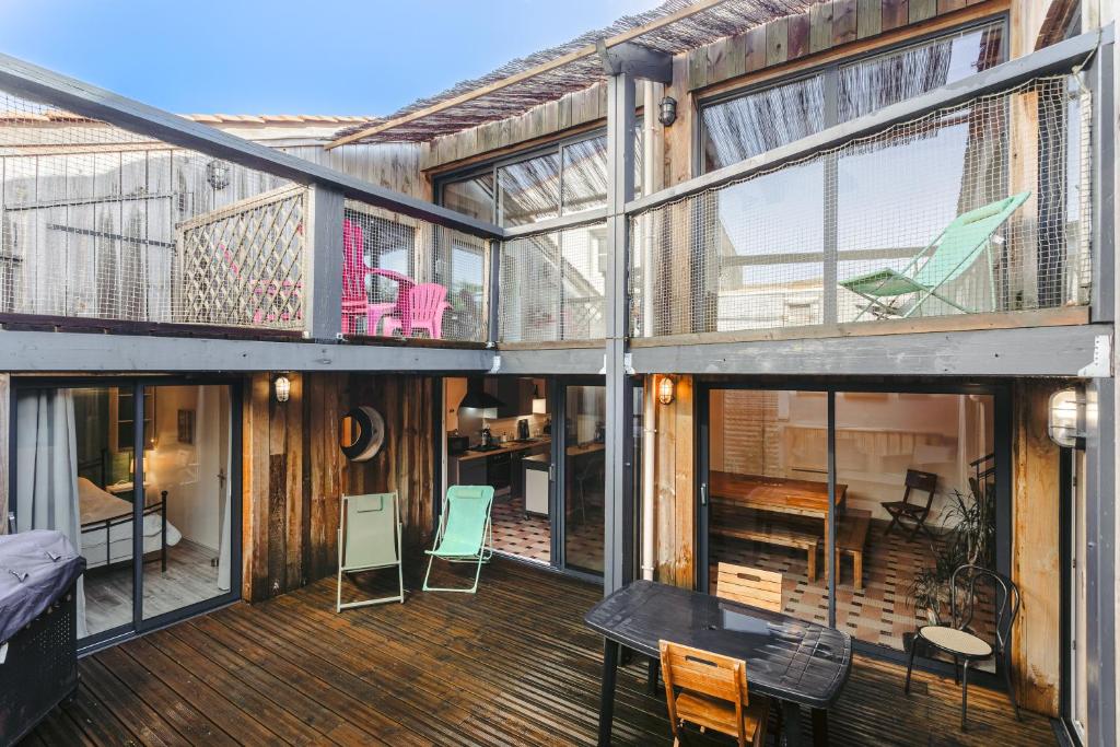 ein Haus mit einer großen Terrasse mit Stühlen und Tischen in der Unterkunft Couleur Patio, Loft Atypique, Sauna in Saint-Denis-dʼOléron