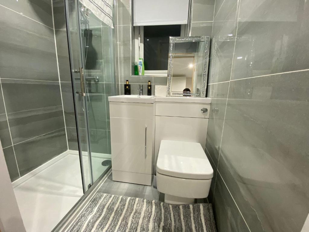 y baño con aseo, ducha y espejo. en Moore Place, en Houghton Regis