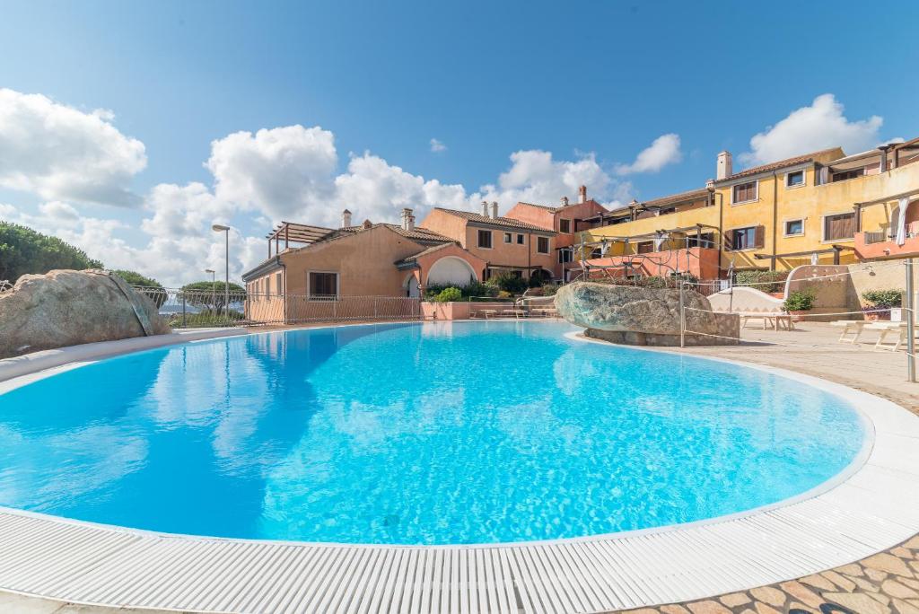 a large blue swimming pool with buildings in the background at C 207 Puntavilla - Vista Piscina in La Maddalena