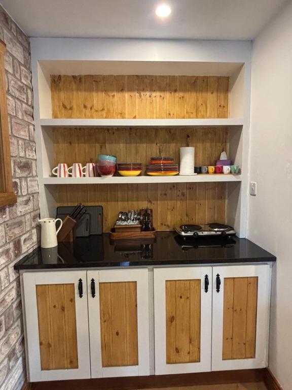 a kitchen with white cabinets and a black counter top at Kells Yard in Feevaghmore