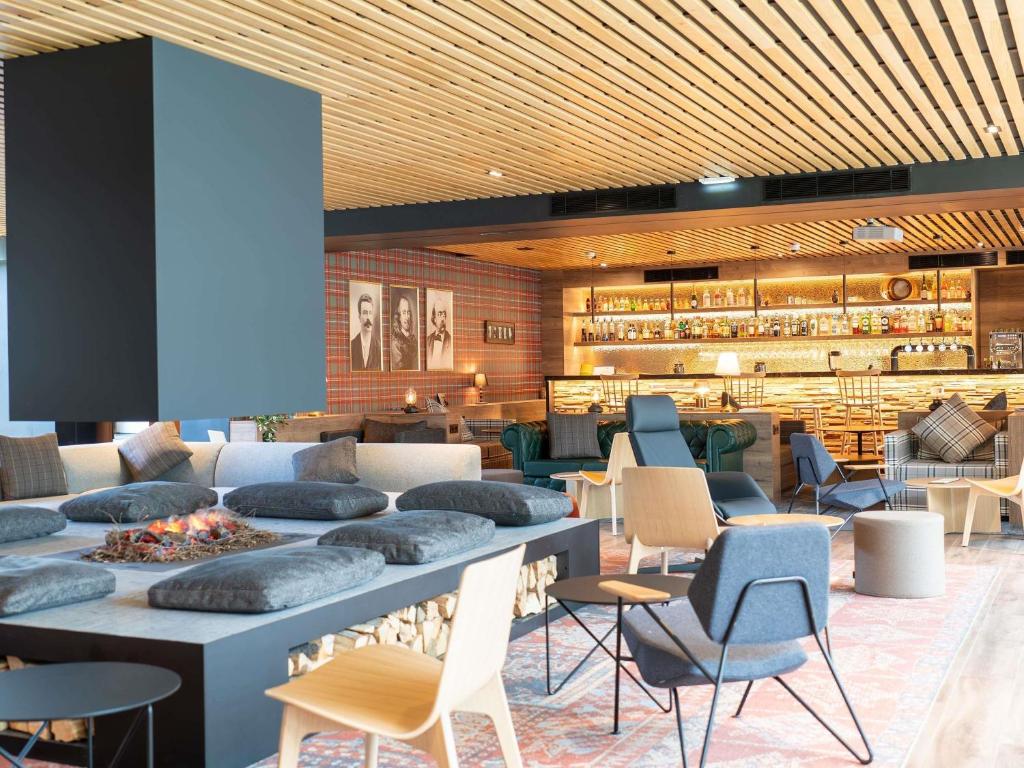 a lobby with tables and chairs and a restaurant at Novotel Rouen Sud Zenith Parc Expo in Saint-Étienne-du-Rouvray